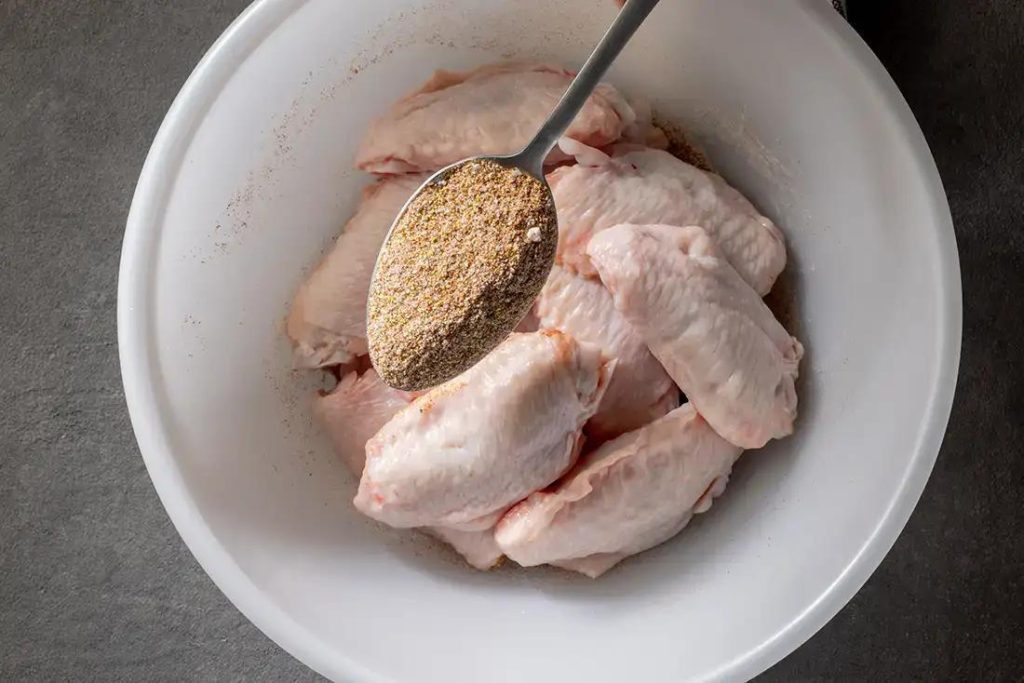 fresh raw chicken wings in bowl of spices