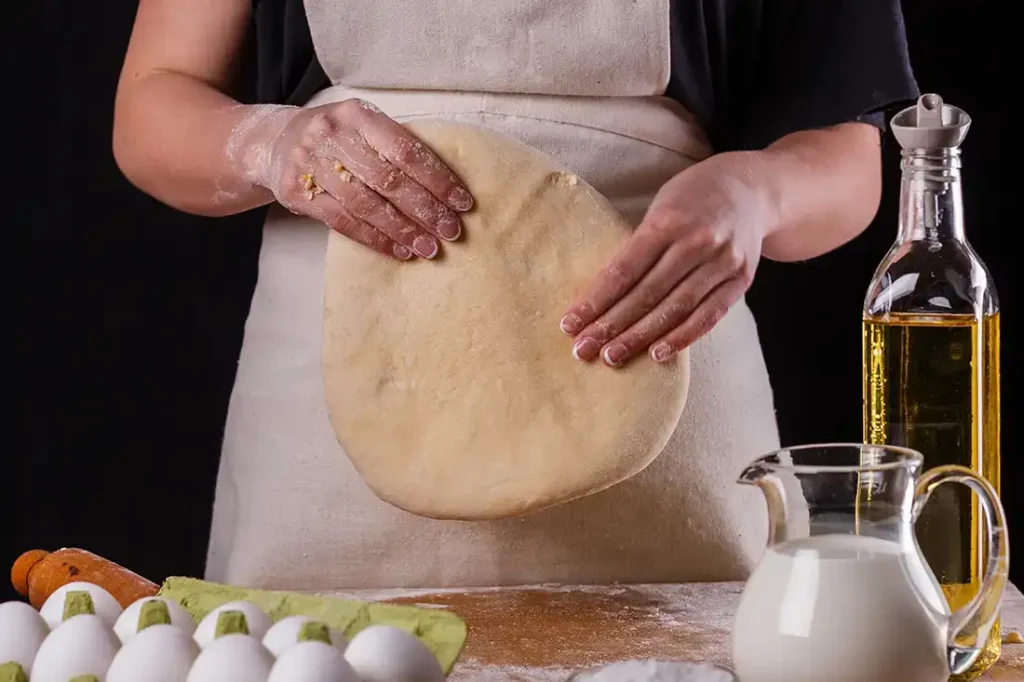 woman-in-apron-kneading-Food-Nanny-Pizza-dough-on-board